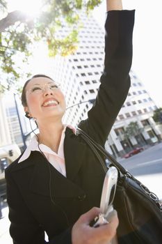 Low angle view of happy businesswoman waving hand with building in the background