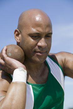 African American male shot putter ready to throw metal ball