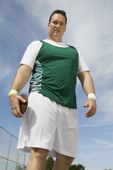 Portrait of male athlete holding discus against sky
