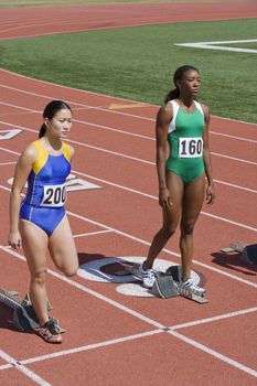 Multiethnic female athletes at starting blocks on race track