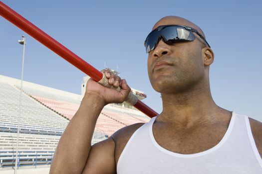 African American athlete about to throw javelin with grandstand in background