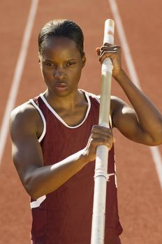 African American female pole vaulter holding pole on field