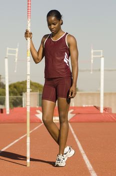 Full length of African American female pole vaulter standing with pole