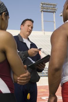 Trainer instructing male athletes in stadium