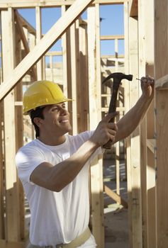 Side view of a construction worker in hardhat working on timber frame