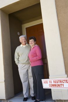 Portrait of happy senior couple standing at the doorway of their new house