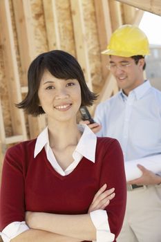 Portrait of a Chinese woman smiling with foreman standing in background at construction site