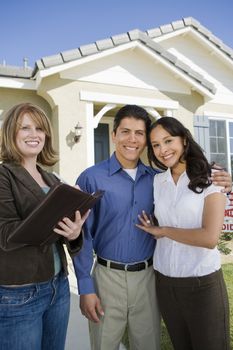 Portrait of Loving Hispanic couple with a female real estate agent