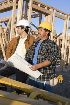 Male construction workers with blueprint at site