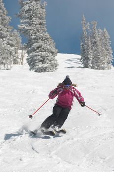 Full length of a young woman skiing down snow covered slope