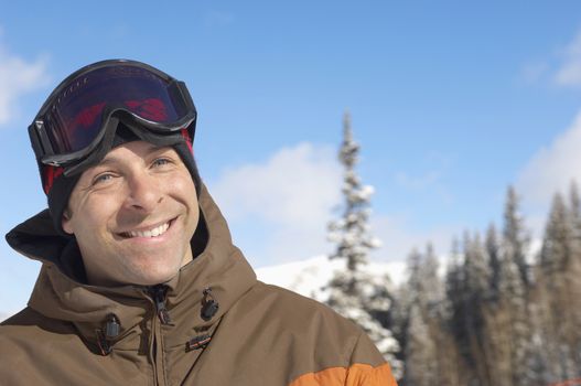 Portrait of happy mature skier against sky