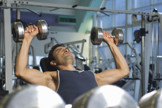 Selective focus of man lifting weights at a gym