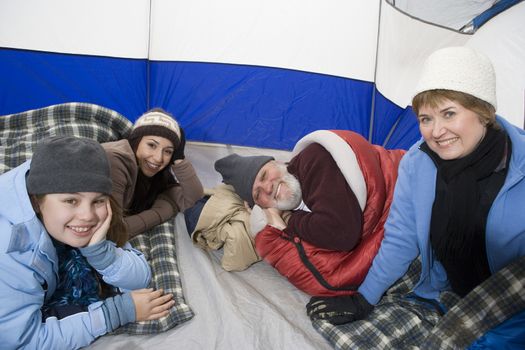Multi-generational family relaxing in camping tent