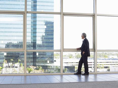 Full length of middle age businessman looking out of office window