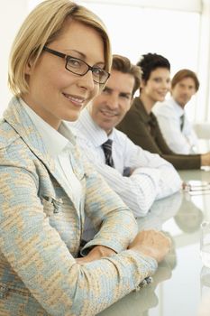 Beautiful confident businesswoman with colleagues at conference table
