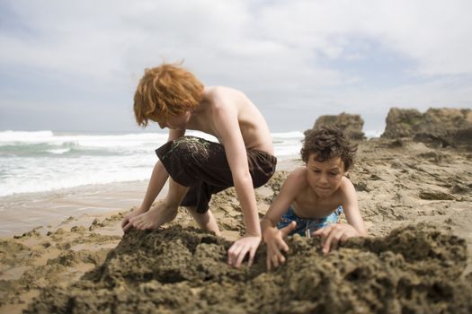 Two pre-teen boys playing in sand on beach