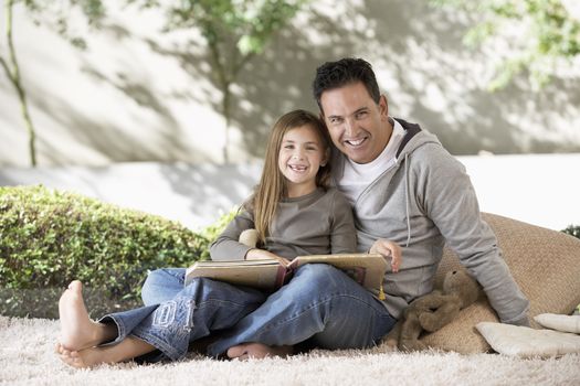 Portrait of happy father and daughter sitting together with photo album