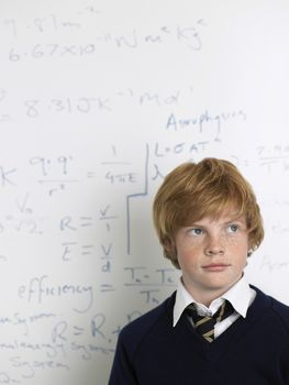 Teenage boy standing by whiteboard in math class