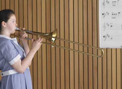 Side view of high school girl playing trombone in music class