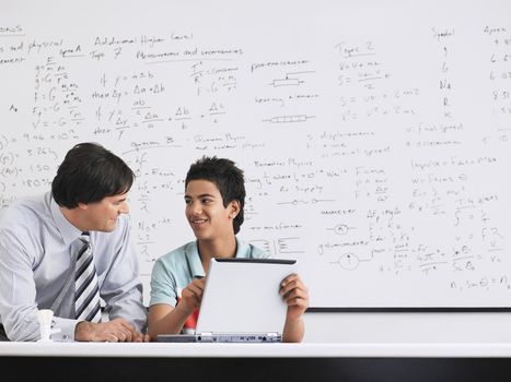 Teacher and student using laptop sitting in physics classroom