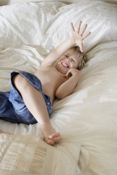 Cheerful boy lying in bed at home