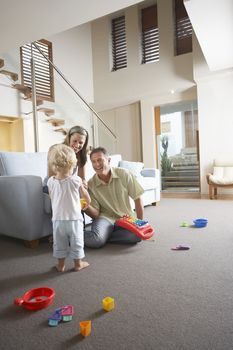 Happy parents and son playing with toy at home