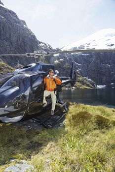 Hiker climbing out of helicopter on mountain top