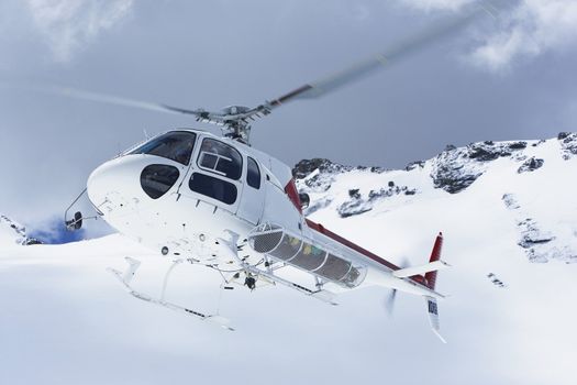 Helicopter Flying Over Snowy Mountain Peaks