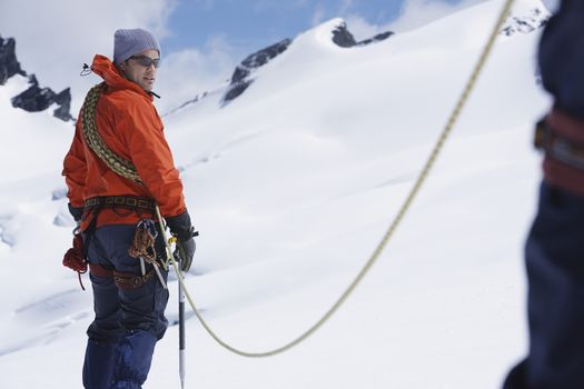 Male hiker connected to safety line in snowy mountains