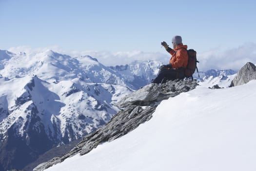 Male climber taking picture of snowy mountains on peak
