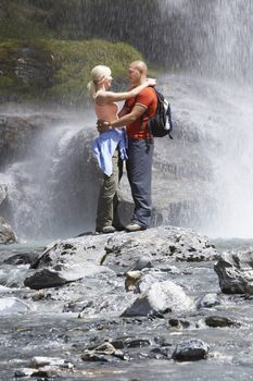 Couple embracing under spray of waterfall
