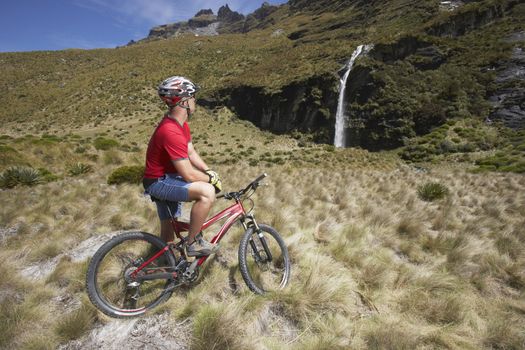 Cyclist looking at waterfall in field
