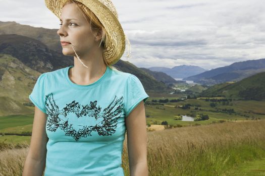 Young contemplative woman wearing cowboy hat against fields