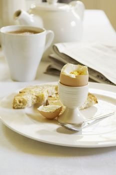 Closeup of half eaten hard boiled egg on dining room table with tea