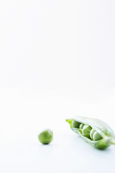 Open pea pod containing peas and single pea close-up