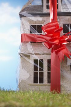 Model house gift-wrapped with red ribbon and bow close-up