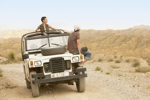 Young couple in four-wheel-drive looking at mountain range