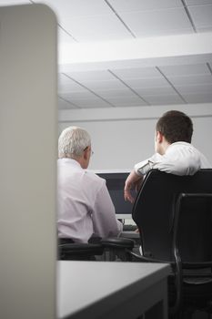Rear view of business people using computer in office cubicle