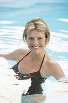 Portrait of beautiful middle aged woman in swimwear swimming in pool
