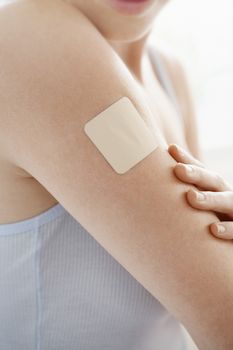 Midsection woman with nicotine patch on arm over white background