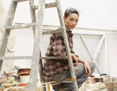 Female interior decorator sitting on ladder in work site portrait