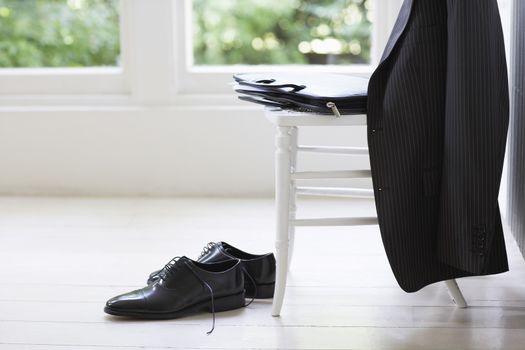 Business suit, case and formal shoes at home