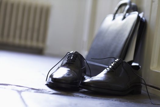 Closeup of formal shoes and briefcase on floor