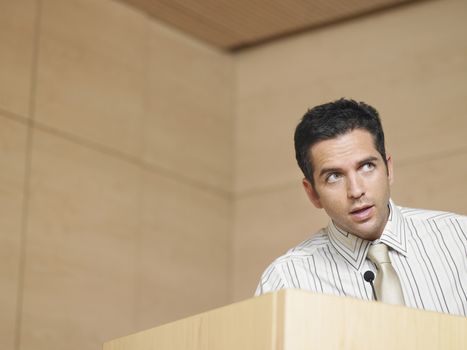 Young businessman talking into microphone in conference room
