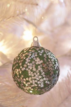 Closeup of star covered bauble hanging on Christmas tree
