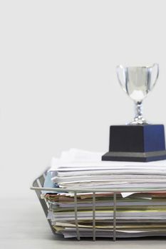 Trophy on stack of file folders over white background