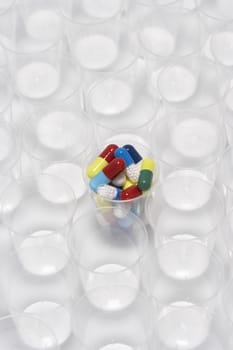 Capsule pills in a plastic cup surrounded by empty plastic cups