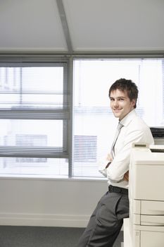 Businessman leaning against office photocopier portrait