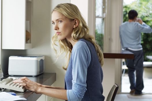 Side view of a worried young woman using computer at home