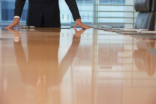 Midsection of a businessman standing with hands on conference table